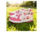 Chaussures pour enfants roses et blanches avec des personnages de dessins animés sur l'herbe.