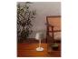 Lampe de table portable sur une table en bois extérieure avec plantes et chaise.