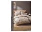 Chambre avec housse de couette et taies d'oreiller à carreaux beiges, tête de lit en bois et tapis en jute.