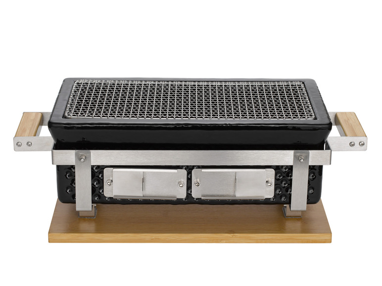 Een zwarte keramische grill met een roestvrijstalen frame en houten handvatten.
