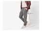 Man in grijze joggingbroek, beige t-shirt en bruin jack, leunend op een kruk.