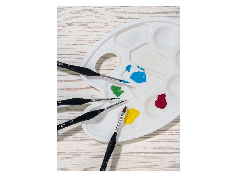 Palette de peinture et pinceaux Crelando sur fond de bois blanc.
