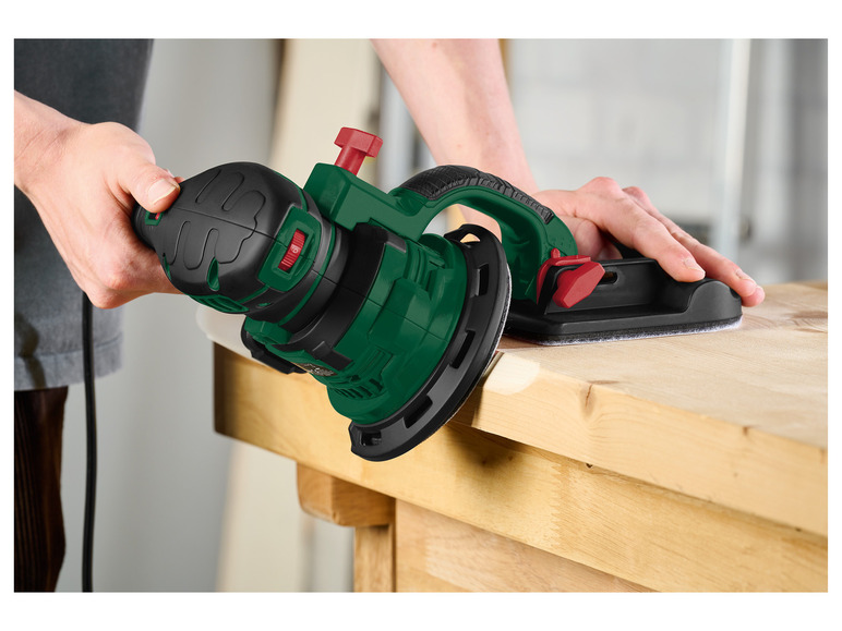 Een groene schuurmachine wordt gebruikt om hout te schuren.