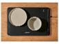 Chauffe-plats noir avec deux assiettes et commandes de température sur une table en bois.