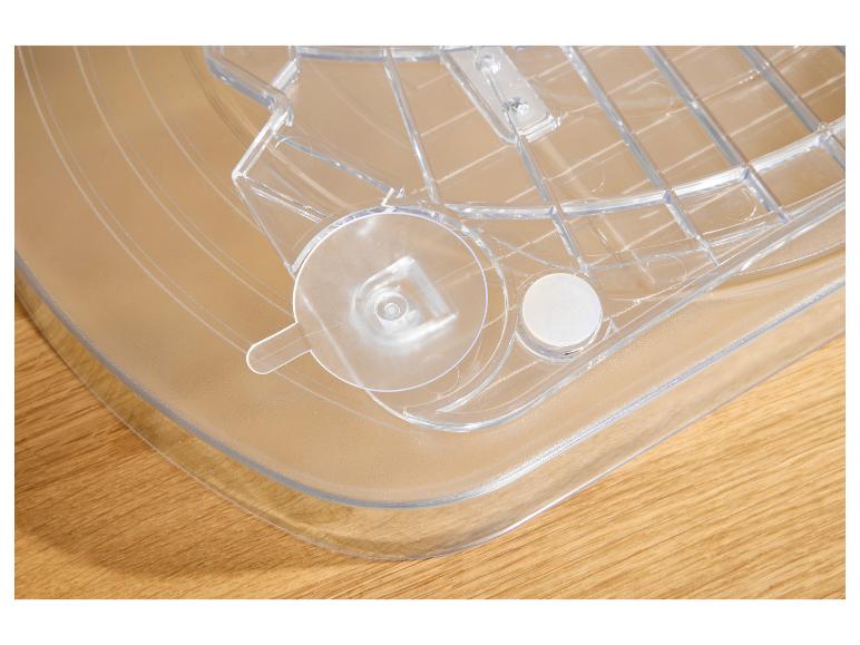 Plateau en plastique transparent avec motif quadrillé et fixations rondes sur une surface en bois.