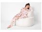 Vrouw in witte pyjama met rode harten, zittend op een witte fauteuil.