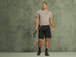 Man in een grijs T-shirt en zwarte shorts met wandelstokken.