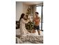 Vrouw in nachthemd en man in boxershorts kussengevecht voor een kerstboom.
