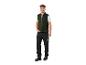 Homme souriant portant un gilet vert foncé, un t-shirt blanc et un pantalon de travail noir.