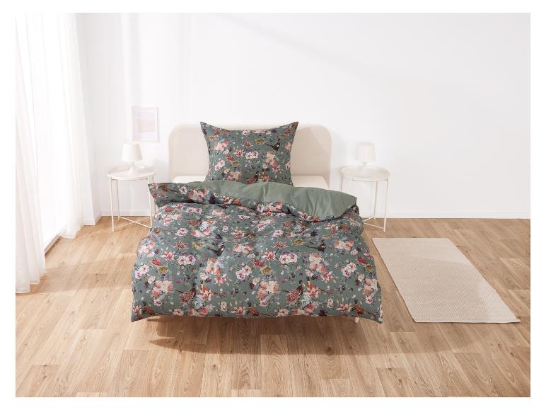 Parure de lit florale avec des oiseaux, sur un lit en bois clair.