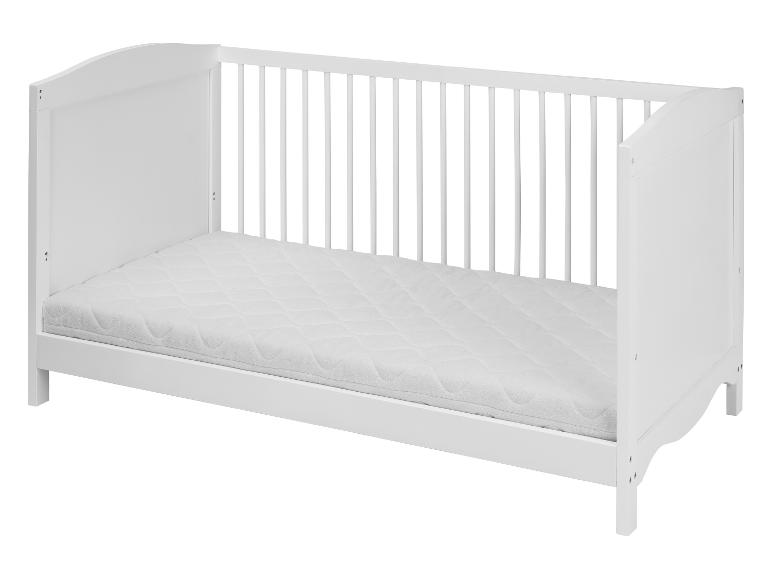 Un lit bébé blanc avec un matelas.