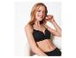 Femme souriante en soutien-gorge et culotte noirs, assise sur une chaise.