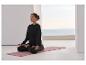Femme méditant sur un tapis de yoga, vêtue d'un sweat-shirt et d'un pantalon noirs.