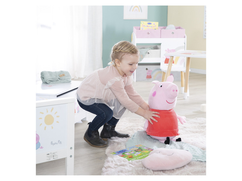 Een meisje speelt met een Peppa Pig knuffel en een boek.