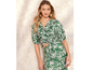 Een vrouw draagt een groene top en rok met bladerenprint.