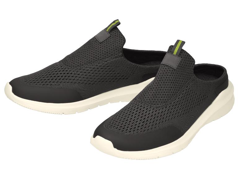 Een paar zwarte instap sportschoenen met groene accenten en witte zolen.