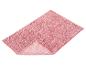 Tapis de bain rectangulaire rose avec surface texturée et bouclée, plié pour montrer le dessous