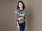 Une femme avec un pull gris à motif scandinave et un jean bleu.