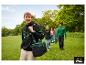 Man met zwarte hoodie en groene koeltas, vrienden met drankjes in een weide.
