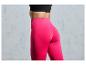 Een vrouw draagt ​​een roze leggings en een zwarte sportbeha.