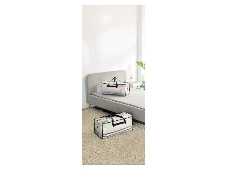 Twee transparante opbergtassen met handvatten, één op een bed en één op een vloerkleed.