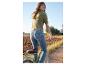 Een vrouw fietst in een groene trui en blauwe jeans.