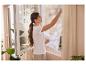 Femme ouvre fenêtre avec moustiquaire, laissant entrer l'air frais.