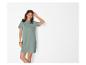 Femme en robe t-shirt vert sauge avec des lunettes de soleil sur la tête, souriante.