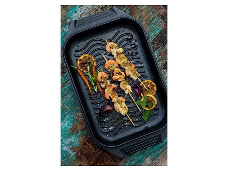 Brochettes de crevettes grillées avec citron et oignon rouge dans une poêle à griller.