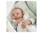 Bébé dans une gigoteuse vert clair avec un imprimé animaux et arbres.