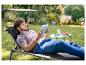 Homme se détend sur une chaise longue de jardin avec pare-soleil, lisant un livre.