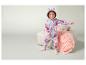 Een kind in een roze unicorn onesie staat op een bank.