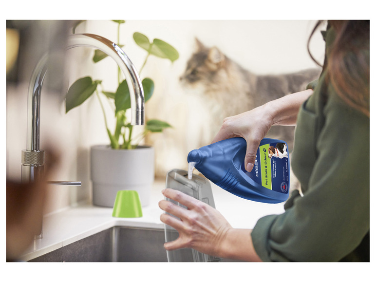 Une personne verse du liquide Bissell Pet Stain & Odour dans un appareil.