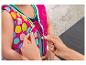 Mains fermant la fermeture éclair d'un gilet de natation coloré à pois pour enfant.