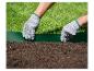 Mains gantées de jardinage installant une bordure de pelouse verte entre l'herbe et la terre.