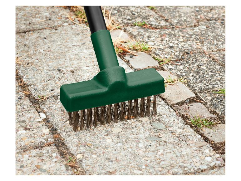 Onkruidborstel met metalen borstels verwijdert onkruid tussen tegels
