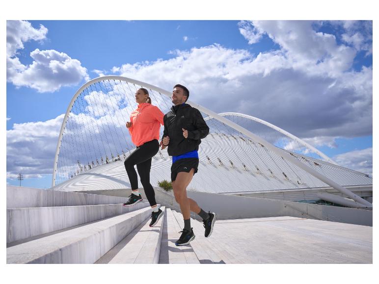 Twee mensen rennen trappen op in sportjacks en leggings.