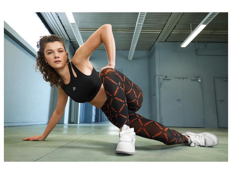Vrouw in zwarte sportbeha en bedrukte legging, aan het sporten.