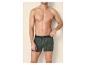 Man zonder shirt in groene boxershorts met palmbomenprint.