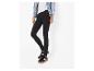 Femme portant un jean skinny noir, un haut blanc, une veste en jean et des baskets noires.