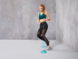 Een vrouw in sportkleding rent over blauwe kegels.