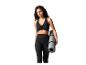 Femme en brassière de sport noire et legging tenant un tapis de yoga