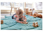 Een baby speelt met houten speelgoed op een groene speelmat.