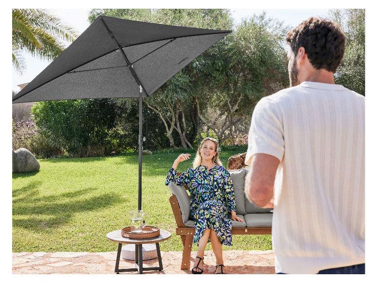 Un parasol gris et un banc en bois dans un jardin.