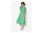 Une femme portant une robe fleurie verte et des baskets blanches.