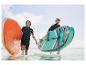 Deux personnes courent dans l'eau avec des paddleboards gonflables.
