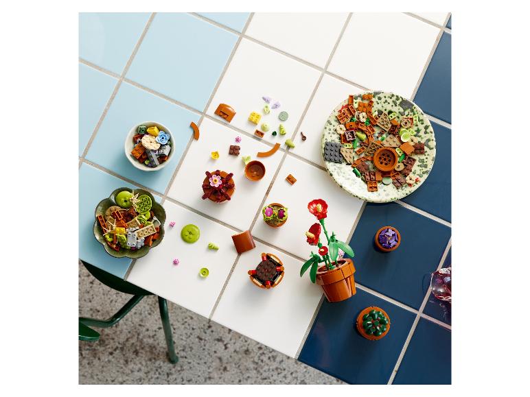 Pièces de collection botanique Lego et plantes assemblées sur une table carrelée.