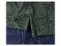 Polo vert foncé à motif de feuilles tropicales, porté sur un jean en denim bleu.