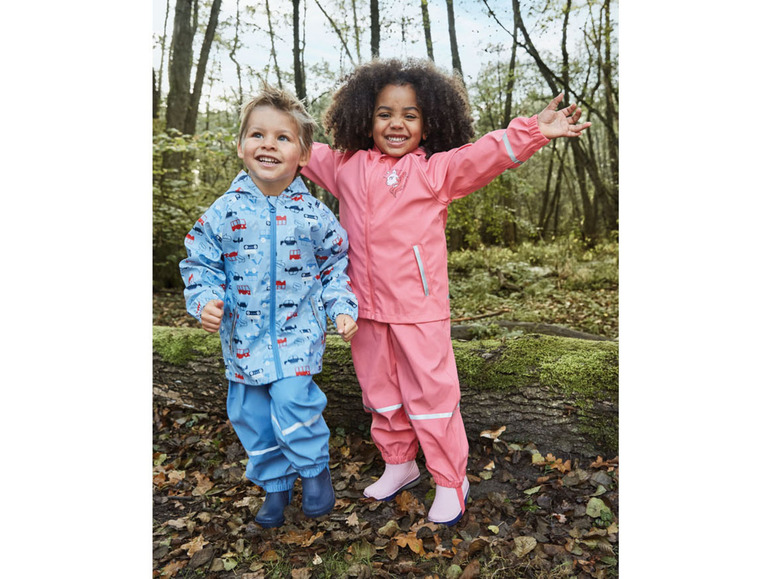 Twee kinderen in regenkleding, een jongen met een blauwe regenjas met auto's en een meisje met een roze regenjas.