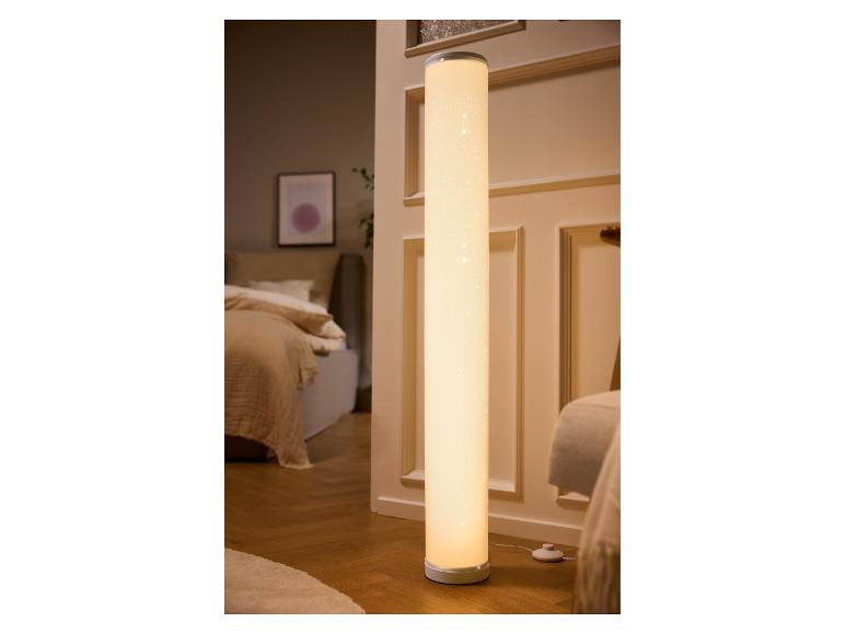 Lichtgevende cilindrische vloerlamp met sterrenpatroon in een slaapkamer.
